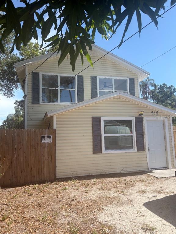 A two-story house with light yellow siding, dark shutters, and a wooden fence — 915 SEMINOLE STREET, CLEARWATER, FL