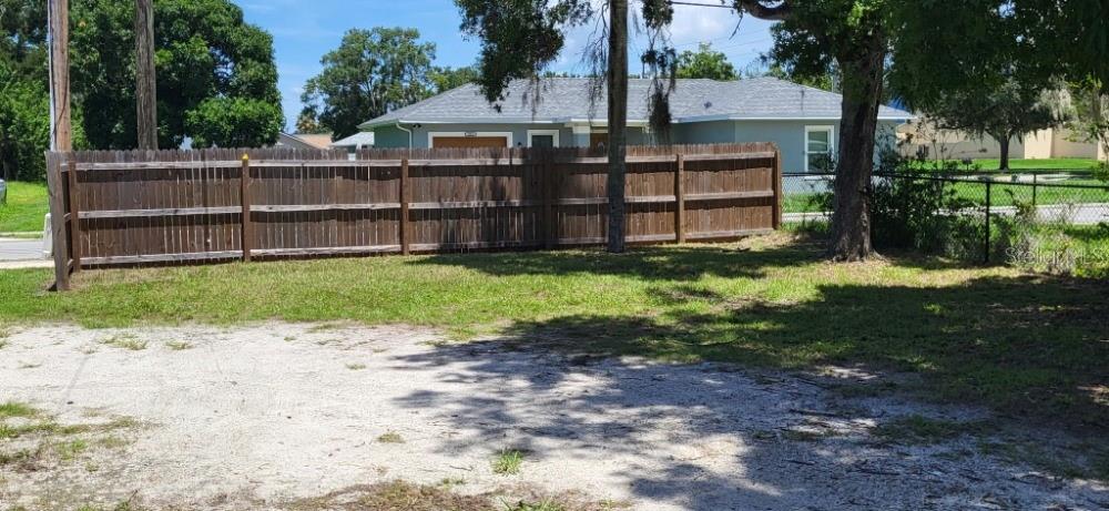 A wooden privacy fence separates a grassy yard from a house with a gray roof — 915 SEMINOLE STREET, CLEARWATER, FL