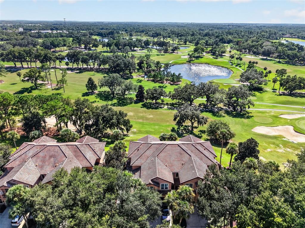 An aerial view shows two multi-story residential buildings overlooking a large golf course with ponds — 901 CAMINO REAL BOULEVARD UNIT 901, HOWEY IN THE HILLS, FL