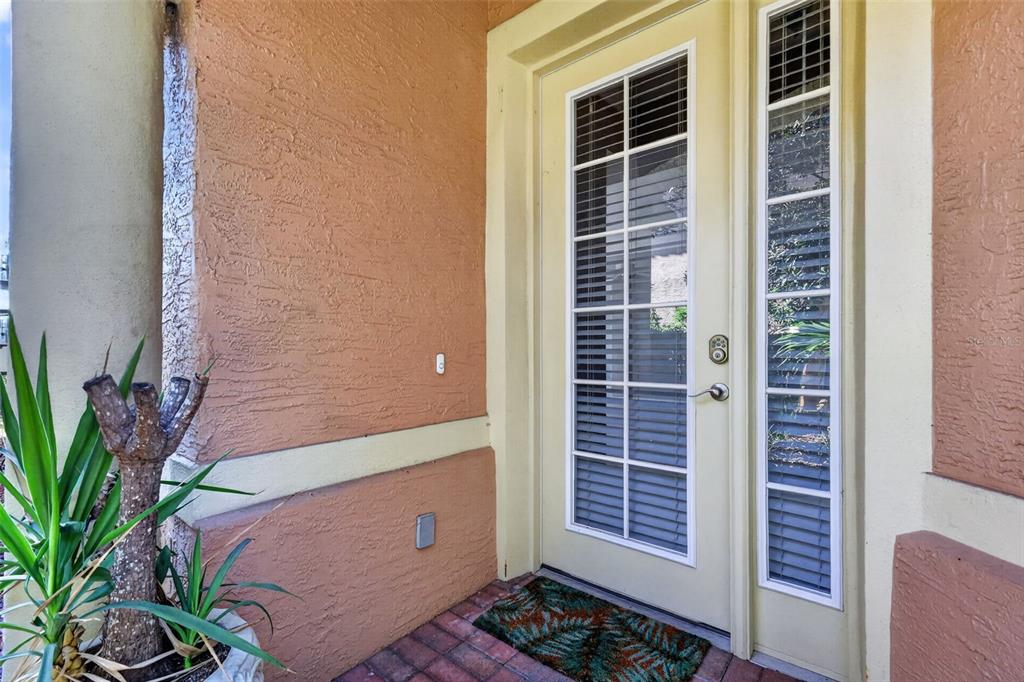 A front entryway features a light-colored door with glass panes, a sidelight, and stucco walls — 901 CAMINO REAL BOULEVARD UNIT 901, HOWEY IN THE HILLS, FL