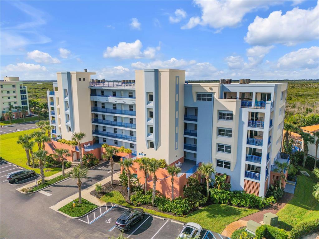 An aerial view of a multi-story apartment building with balconies and a parking lot — 5300 S ATLANTIC AVENUE UNIT 17-207, NEW SMYRNA BEACH, FL