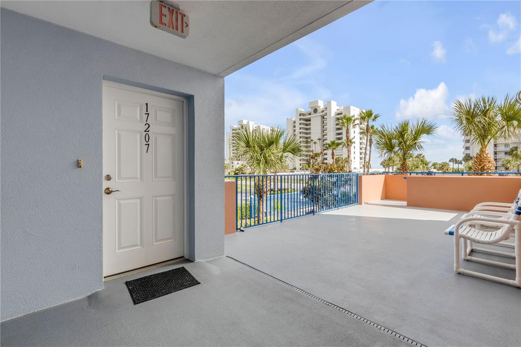 A white door labeled 17207 opens onto a concrete balcony with patio chairs and railings — 5300 S ATLANTIC AVENUE UNIT 17-207, NEW SMYRNA BEACH, FL