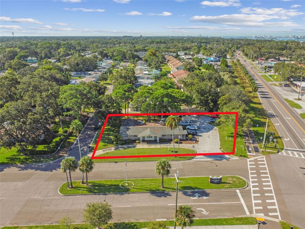 An aerial view shows a single-story building with a parking lot surrounded by trees — 605 PALM BOULEVARD, DUNEDIN, FL