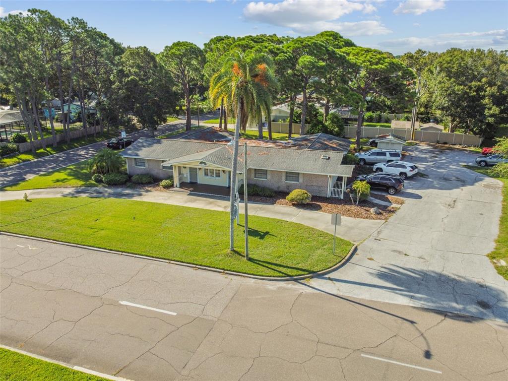 An aerial view of a single-story building with a parking lot and surrounding trees — 605 PALM BOULEVARD, DUNEDIN, FL