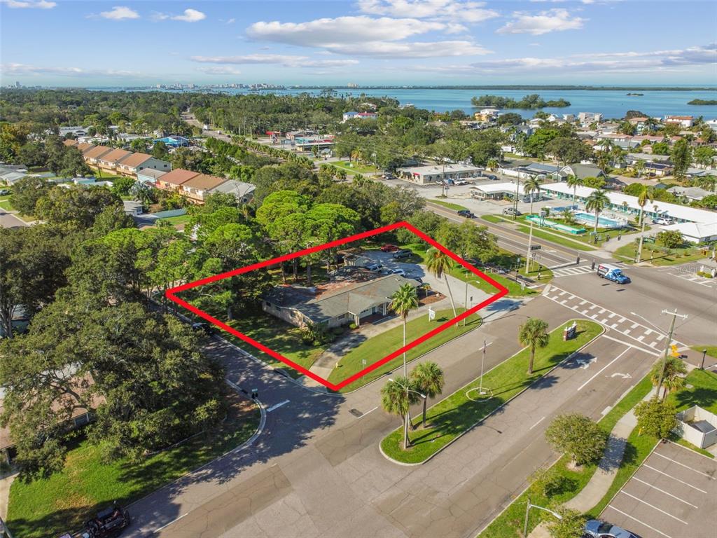 An aerial view shows a single-story building on a corner lot outlined in red — 605 PALM BOULEVARD, DUNEDIN, FL