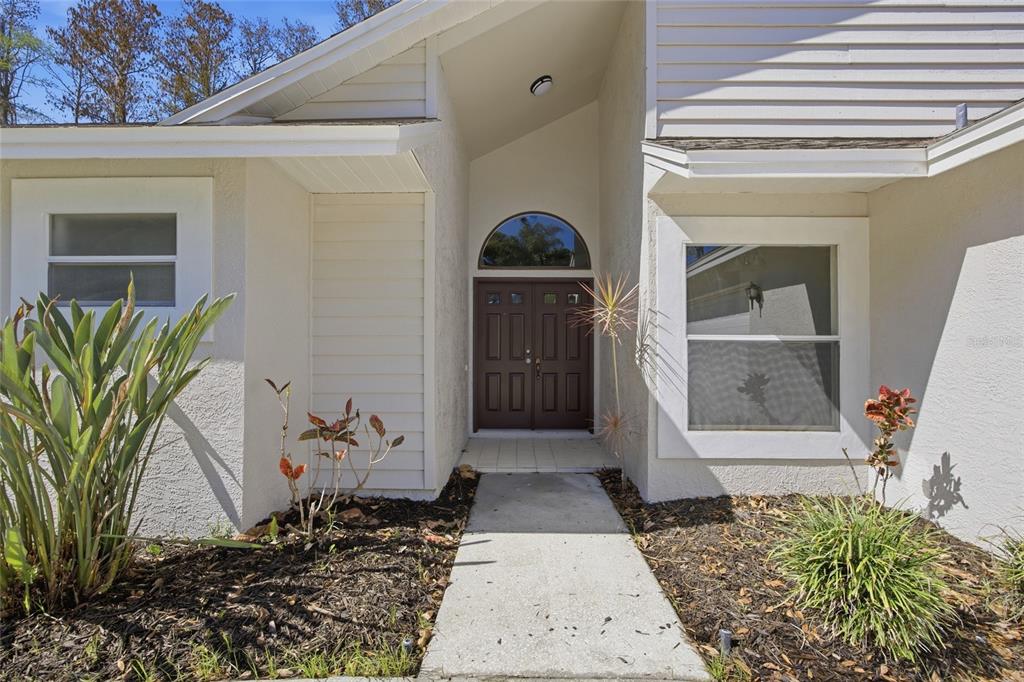 A living room with tile flooring near the entrance, wood-look flooring, and sliding glass doors — 812 CRESTRIDGE DRIVE, TARPON SPRINGS, FL