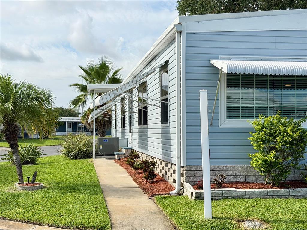 An open-concept living area features light blue walls, wood-look flooring, and a kitchen with dark cabinets — 9790 66TH STREET N UNIT 100, PINELLAS PARK, FL