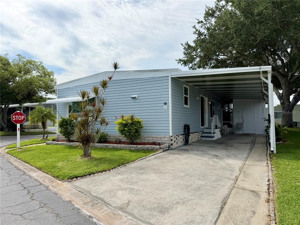 An open-concept living and kitchen area features light wood flooring, blue walls, and white cabinetry — 9790 66TH STREET N UNIT 100, PINELLAS PARK, FL