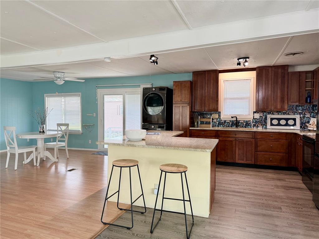 A room with light blue walls, wood-look flooring, a ceiling fan, and sliding glass doors — 9790 66TH STREET N UNIT 100, PINELLAS PARK, FL