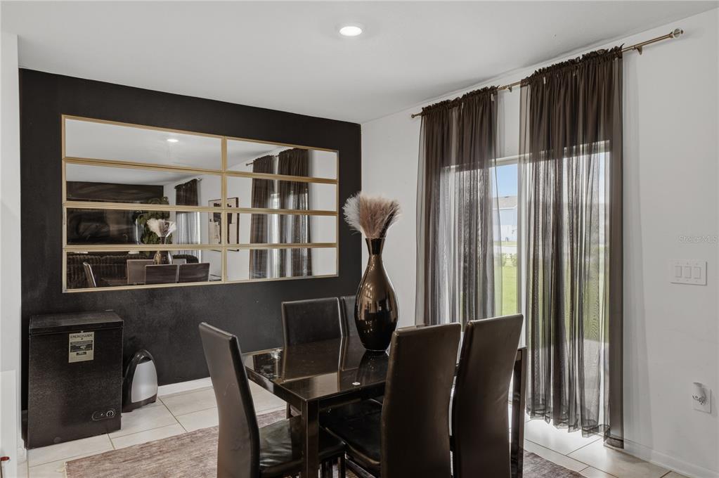 A dining room features a black accent wall with a large mirror and sliding glass doors — 859 TIMBERLAND DRIVE, EAGLE LAKE, FL