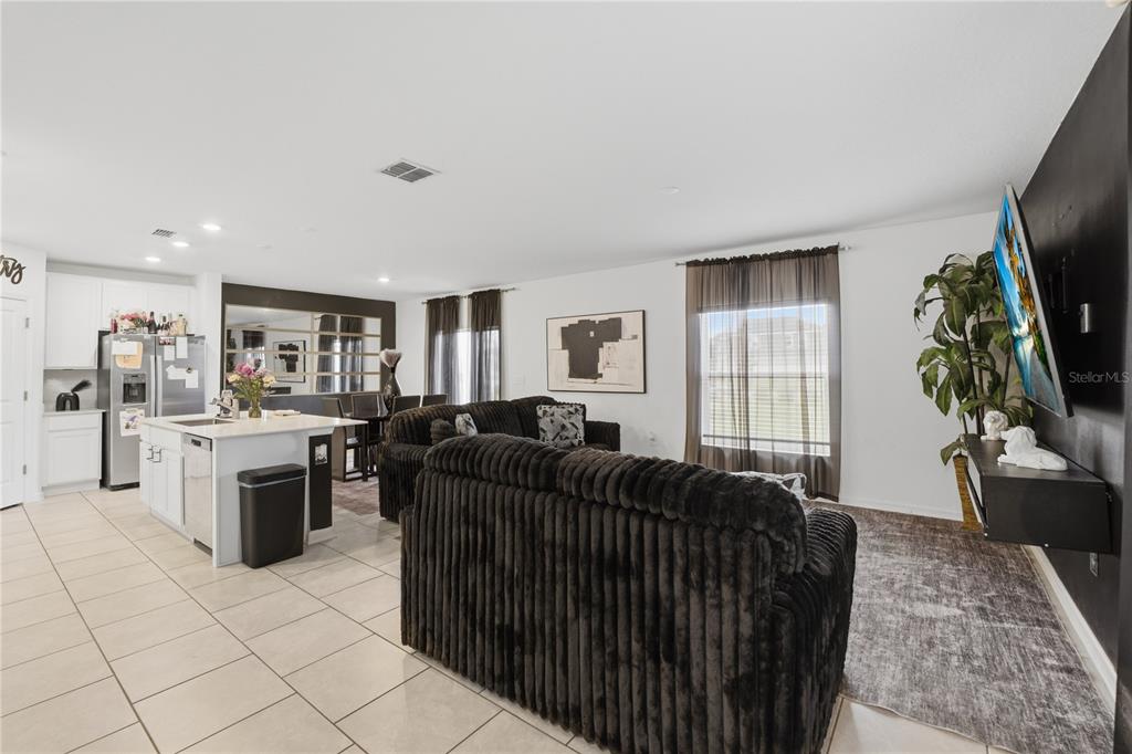 A living room and kitchen area with tile floors, dark furniture, and a wall-mounted television — 859 TIMBERLAND DRIVE, EAGLE LAKE, FL