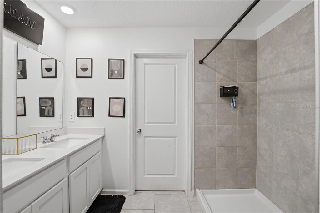 A bathroom features a double vanity, a tiled walk-in shower, and white cabinetry — 859 TIMBERLAND DRIVE, EAGLE LAKE, FL