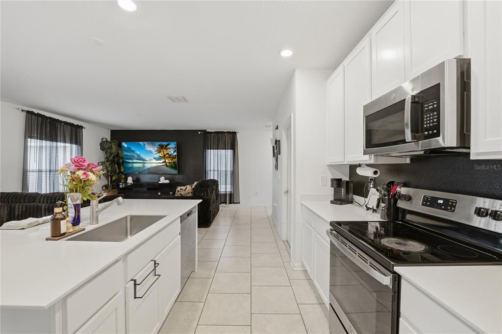 A kitchen with white cabinets and a center island overlooks a living area with dark walls — 859 TIMBERLAND DRIVE, EAGLE LAKE, FL