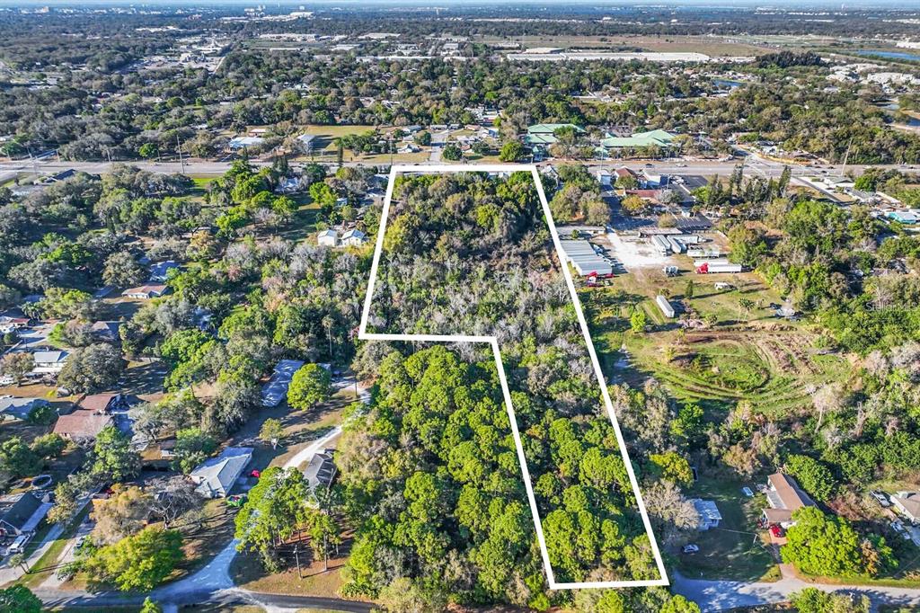 An aerial view shows a wooded, L-shaped vacant lot outlined in white — 2008 53RD AVENUE E, BRADENTON, FL