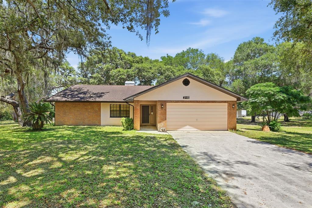 A single-story house with a brick facade, a two-car garage, and a large front yard — 3915 S SPANIEL TRAIL, INVERNESS, FL