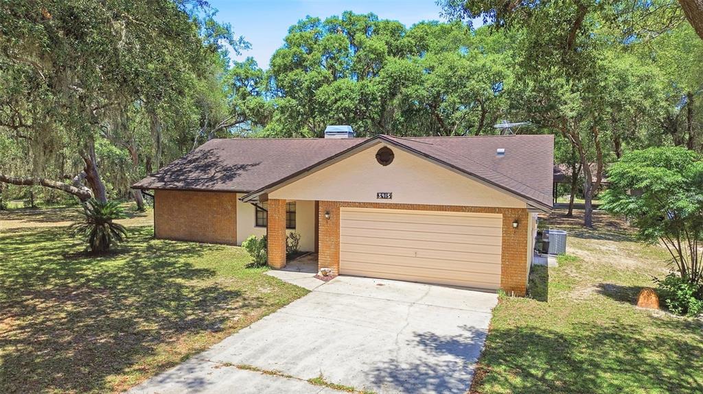 A single-story house with a brick and stucco exterior, a garage, and a large yard — 3915 S SPANIEL TRAIL, INVERNESS, FL