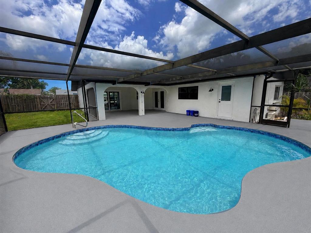 A swimming pool with a screen enclosure sits on a patio next to a house — 303 70TH STREET NW, BRADENTON, FL