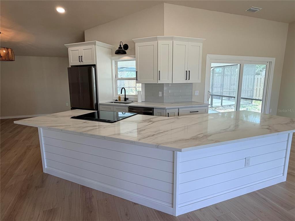 A kitchen features a large white island with a marble countertop and shiplap siding — 303 70TH STREET NW, BRADENTON, FL