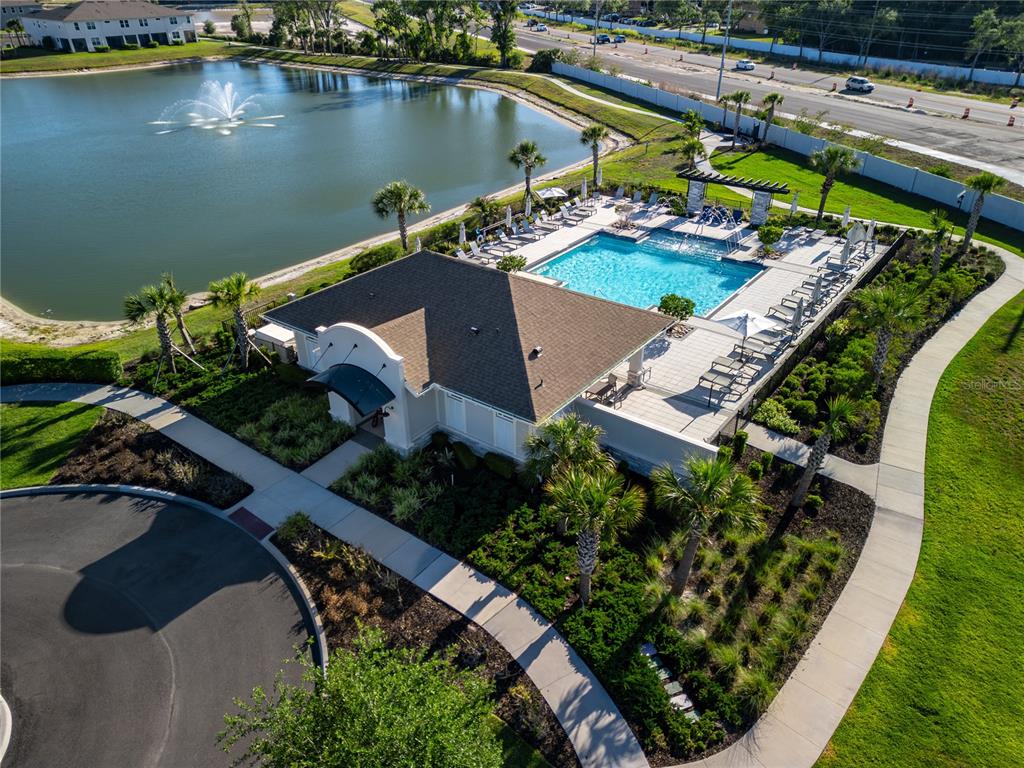 An aerial view shows a community clubhouse with a swimming pool next to a pond — 4062 CLOUD HOPPER WAY, LUTZ, FL
