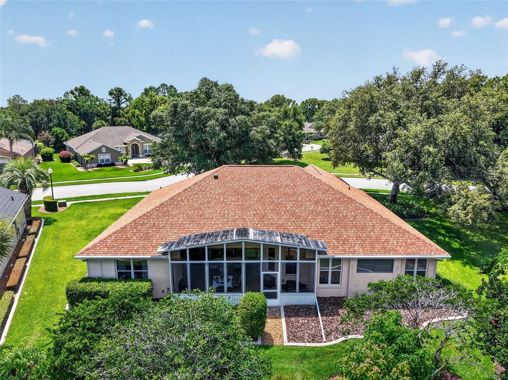An aerial view shows a house with a brown shingled roof and a screened-in porch — 8059 LAUREL RIDGE DRIVE, MOUNT DORA, FL