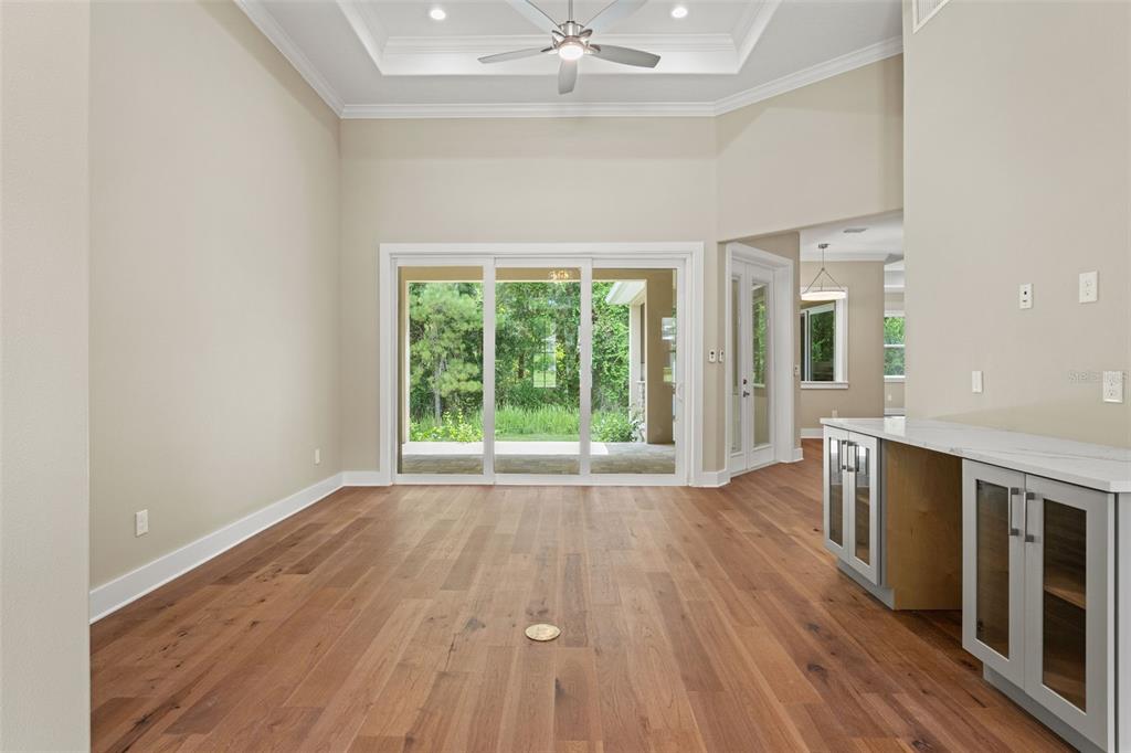 A dining room with wood floors, a tray ceiling, and sliding glass doors to a patio — 5034 ELM LEAF DRIVE, BROOKSVILLE, FL