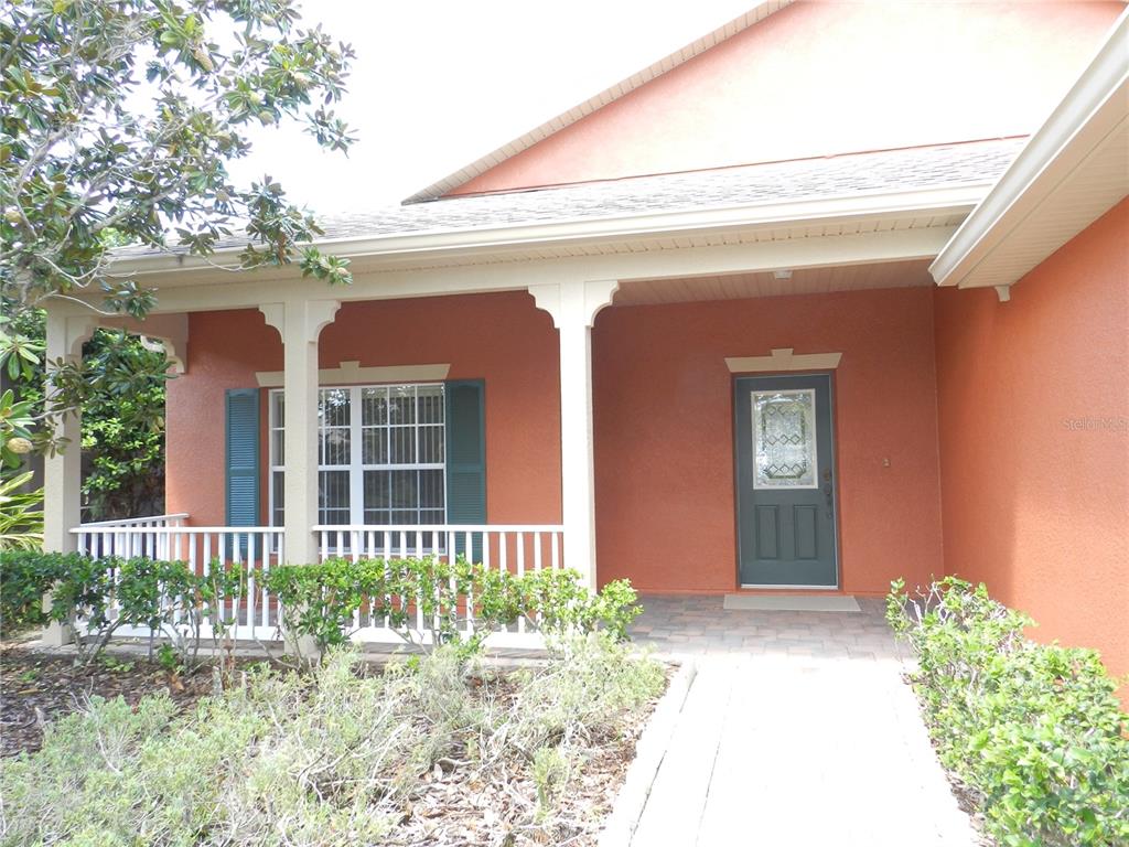 The exterior of a house features a covered porch with white railings and a front door — 542 PORTOFINO DRIVE, POINCIANA, FL