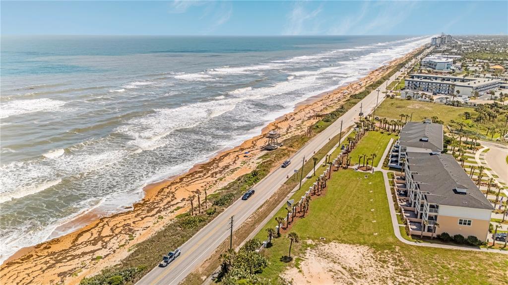 An aerial view shows a coastal road running alongside a sandy beach and apartment buildings — 2222 OCEAN SHORE BOULEVARD UNIT 102B, ORMOND BEACH, FL