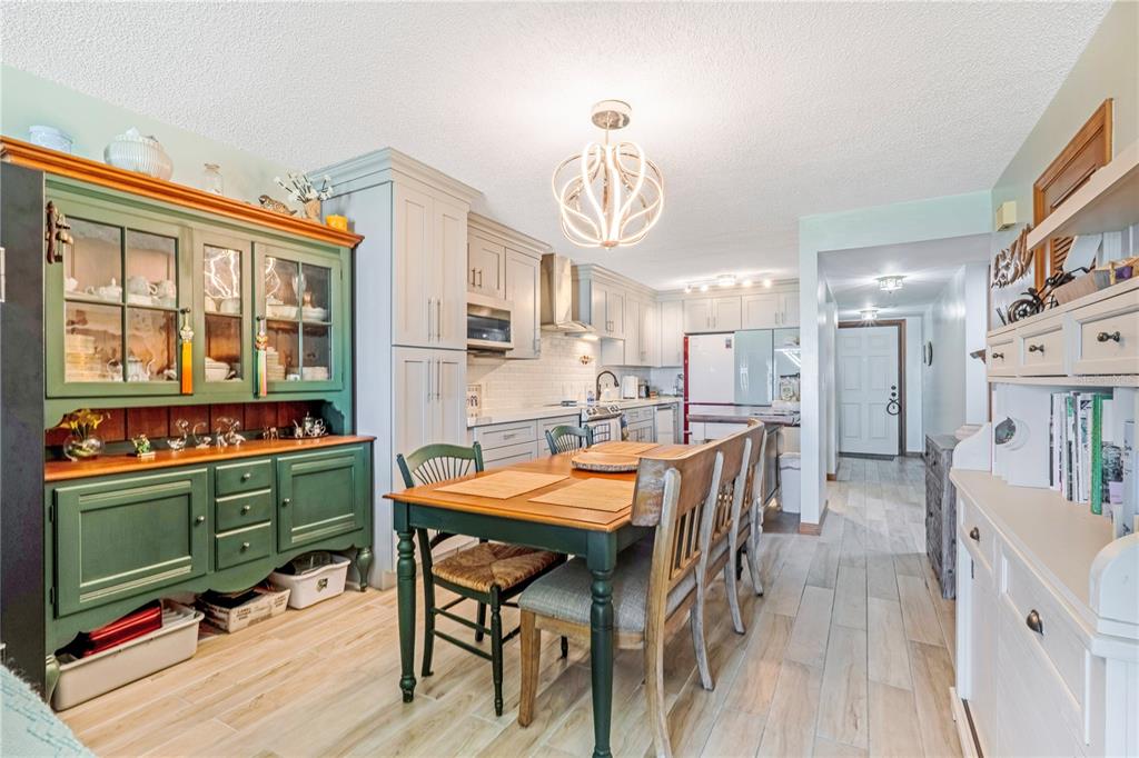 A kitchen and dining area features a green hutch, wooden table, and light-colored cabinetry — 2222 OCEAN SHORE BOULEVARD UNIT 102B, ORMOND BEACH, FL