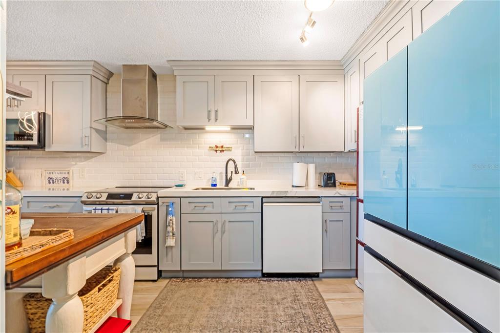 A kitchen features light gray cabinets, a white subway tile backsplash, and a blue refrigerator — 2222 OCEAN SHORE BOULEVARD UNIT 102B, ORMOND BEACH, FL