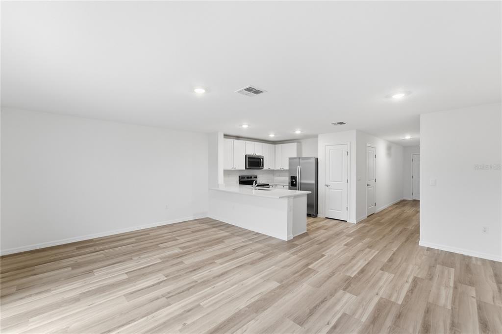 An open-concept kitchen with white cabinets and a breakfast bar overlooks a living area — 8371 GOWER TRAIL, WILDWOOD, FL