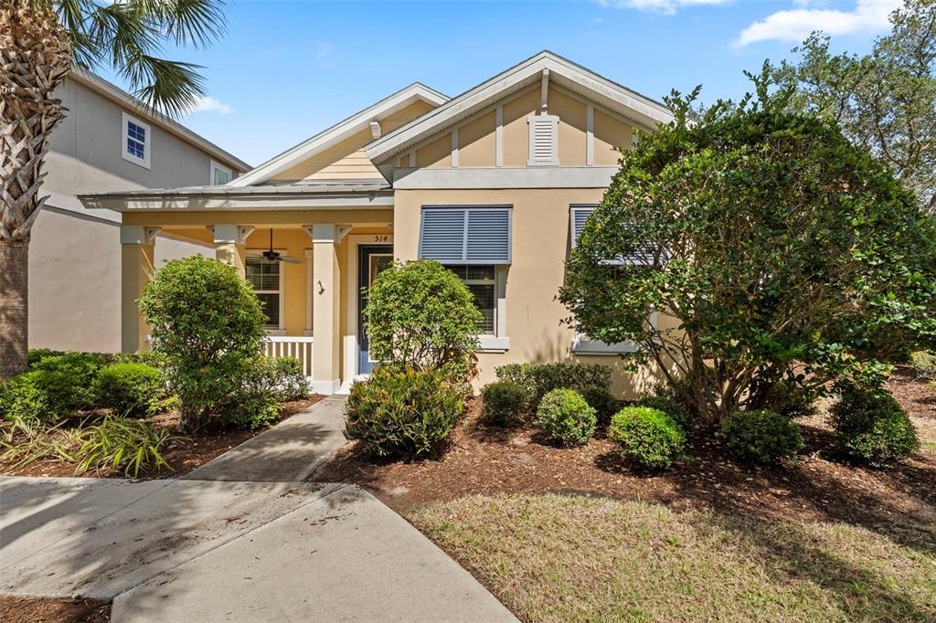 A single-story house with a beige exterior, blue door, front porch, and landscaped yard — 514 WINTERSIDE DRIVE, APOLLO BEACH, FL