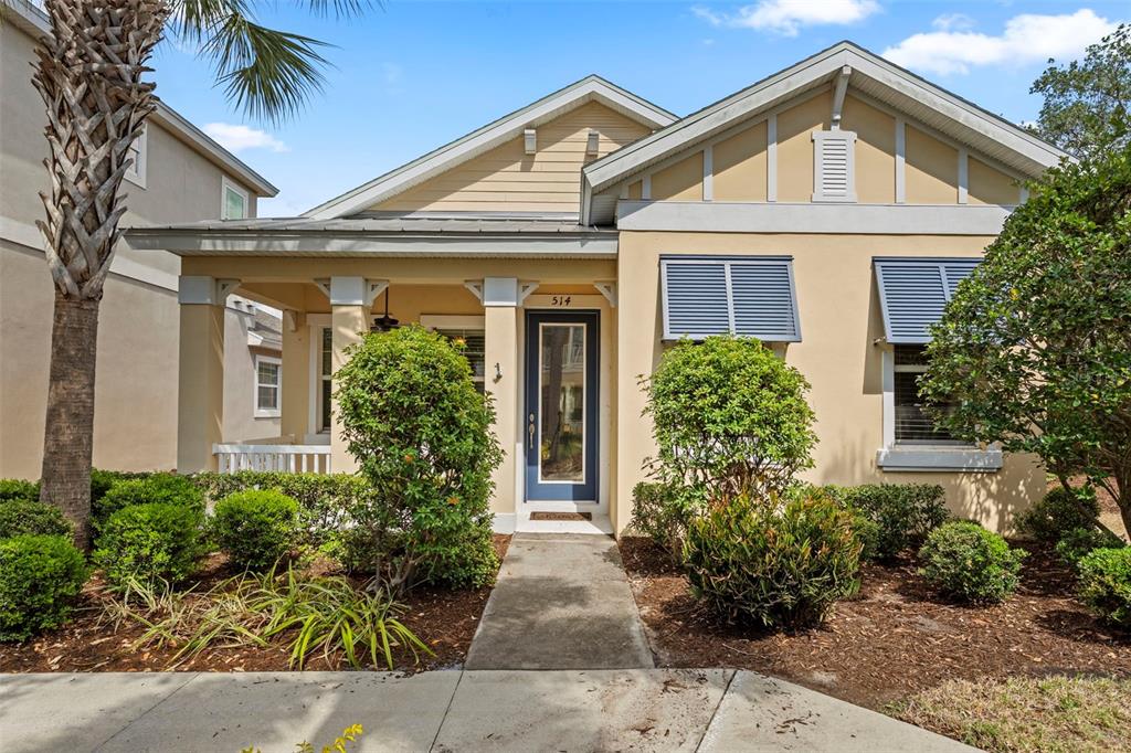 A single-story house with a covered front porch, beige siding, and blue window shutters — 514 WINTERSIDE DRIVE, APOLLO BEACH, FL