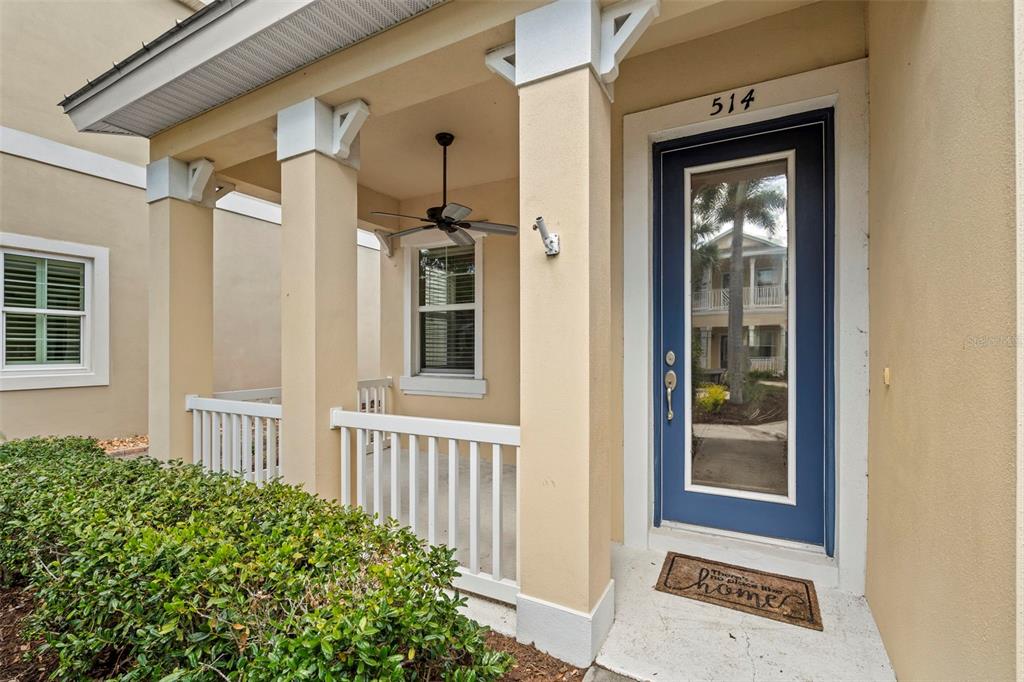 A covered front porch with a ceiling fan, white railings, and a blue front door — 514 WINTERSIDE DRIVE, APOLLO BEACH, FL
