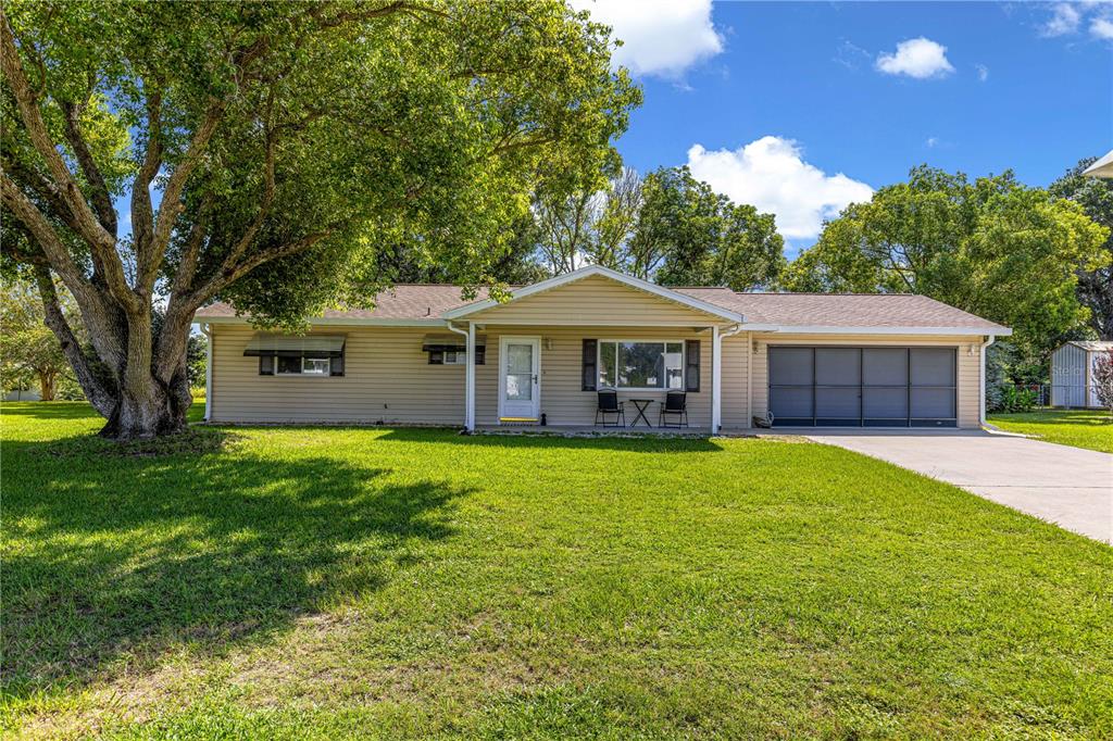 A single-story house with beige siding, a front-facing garage, and a large tree in front — 10765 SW 62ND TERRACE, OCALA, FL