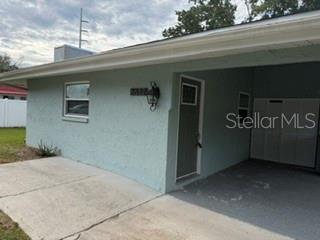 A light blue house exterior features a concrete driveway, a carport, and a dark entry door — 6632 W PELICAN LANE, HOMOSASSA, FL