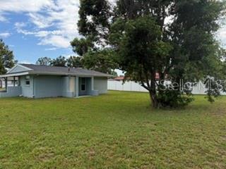 A light blue single-story house sits on a grassy lot next to a large tree — 6632 W PELICAN LANE, HOMOSASSA, FL