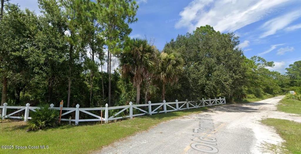 A white wooden fence borders a wooded lot along a dirt road — W SR-40, ORMOND BEACH, FL