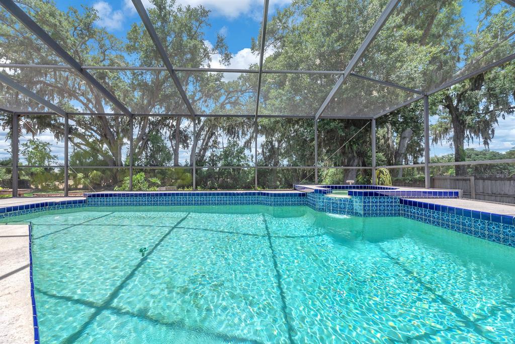 A living room features dark blue sofas, a piano, and a sliding door to a patio — 621 PENN NATIONAL ROAD, SEFFNER, FL