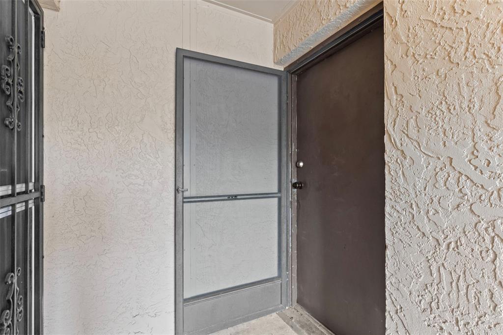 A dark brown entry door with a gray screen door sits against a stucco wall — 5820 N CHURCH AVENUE UNIT 345A, TAMPA, FL