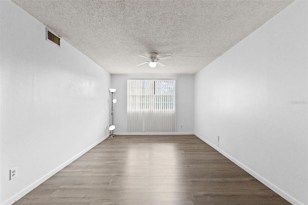 An empty room with white walls, wood-look flooring, a ceiling fan, and vertical window blinds — 5820 N CHURCH AVENUE UNIT 345A, TAMPA, FL