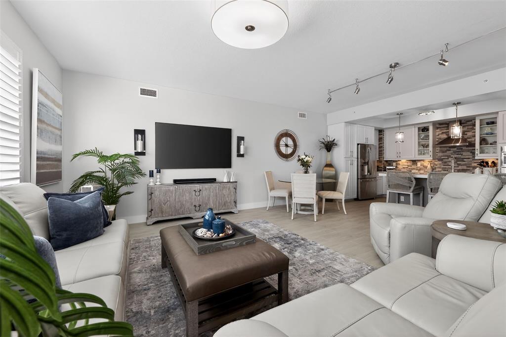 A living room with light gray walls, white leather furniture, and an open-concept kitchen — 915 BAY COLONY DRIVE S UNIT S, JUNO BEACH, FL