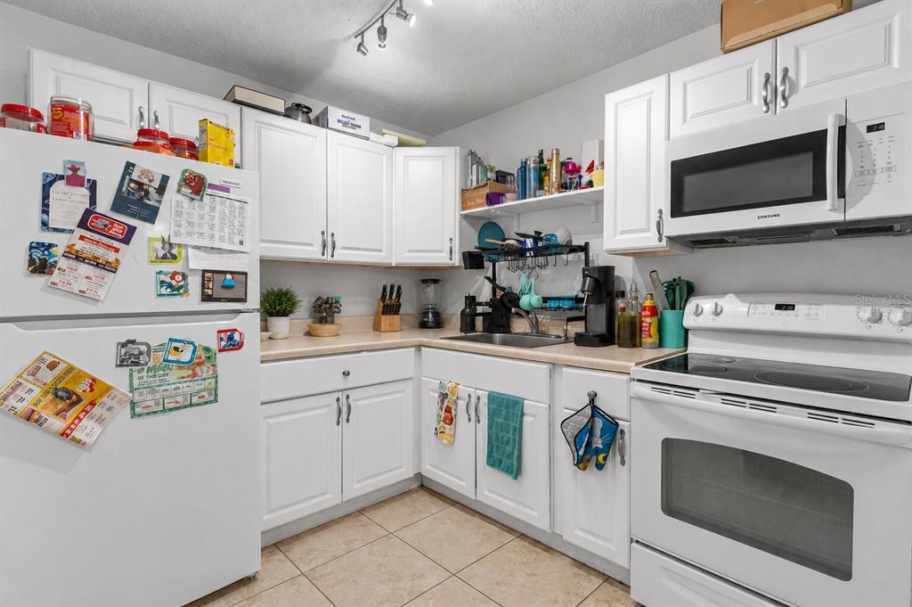 A kitchen with white cabinets, light countertops, a white refrigerator, and a white electric range — 6018 LAKTREE LANE UNIT E, TEMPLE TERRACE, FL