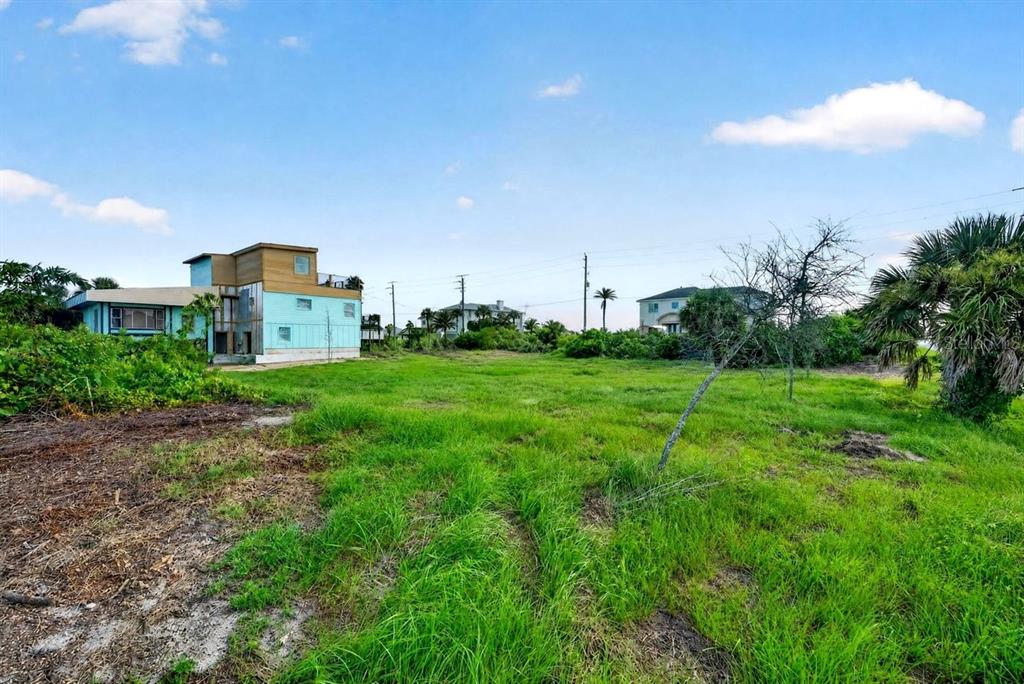 An aerial view shows a vacant, grassy lot situated between coastal houses near a sandy beach — 4738 S ATLANTIC AVENUE, PONCE INLET, FL