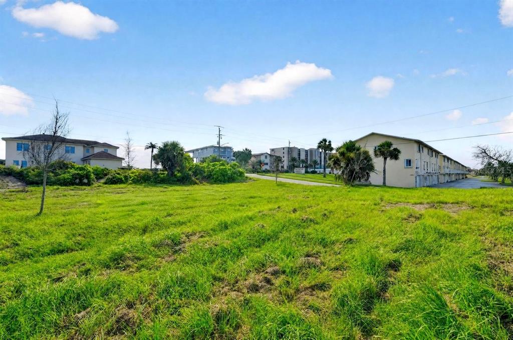 A grassy vacant lot sits in front of a modern two-story house under a blue sky — 4738 S ATLANTIC AVENUE, PONCE INLET, FL