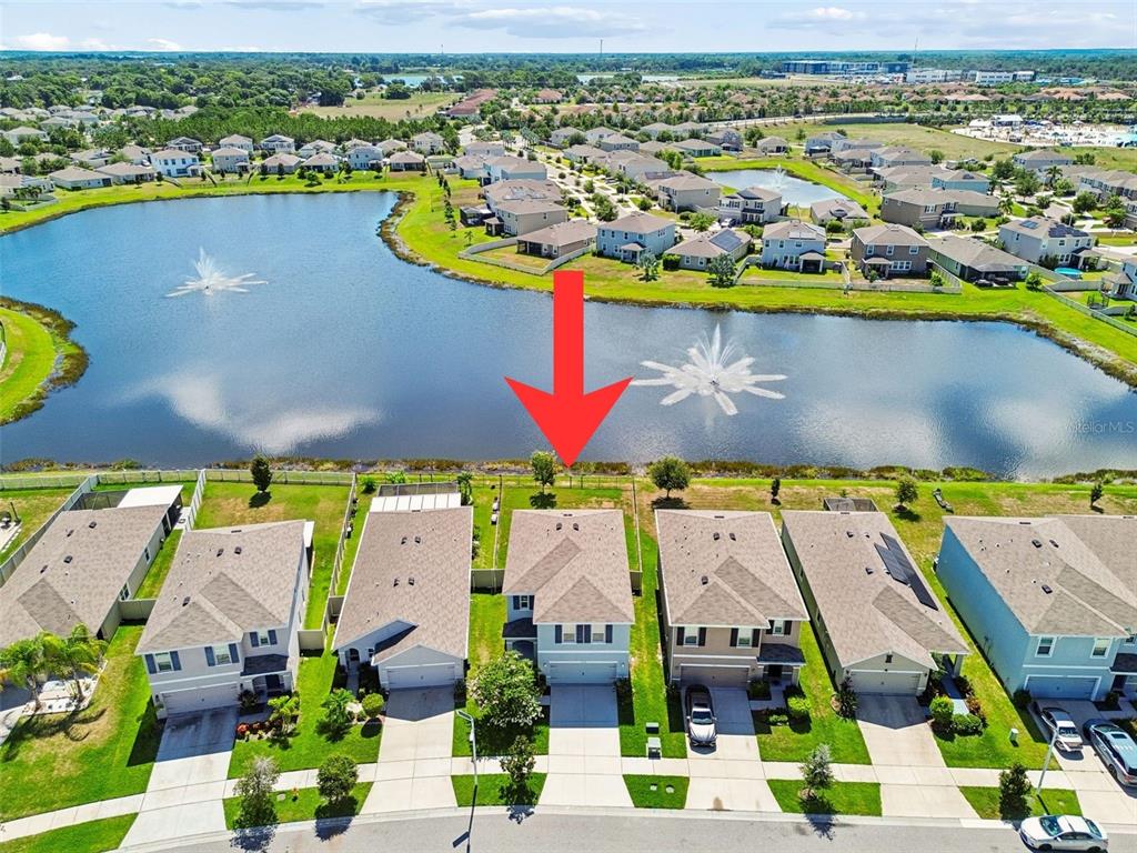 An aerial view shows a suburban house with a backyard facing a large lake — 16734 TRITE BEND STREET, WIMAUMA, FL