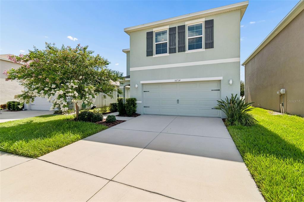 A two-story house with a light green exterior, a two-car garage, and a front lawn — 16734 TRITE BEND STREET, WIMAUMA, FL