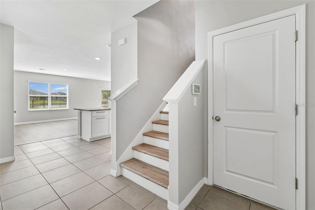 A view of a home interior featuring a staircase, tiled flooring, and a white door — 16734 TRITE BEND STREET, WIMAUMA, FL