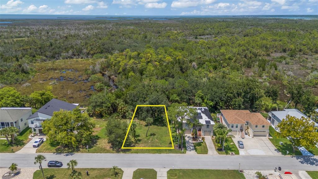 An aerial view shows a vacant residential lot outlined in yellow between two existing houses — GULF WAY, HUDSON, FL