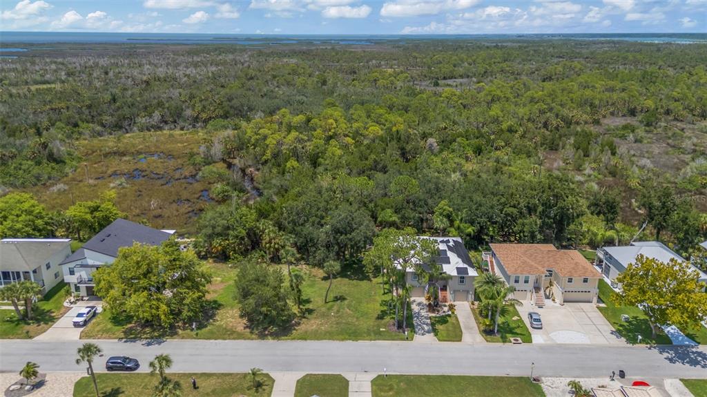 An aerial view shows a vacant residential lot situated between two houses near a wooded area — GULF WAY, HUDSON, FL