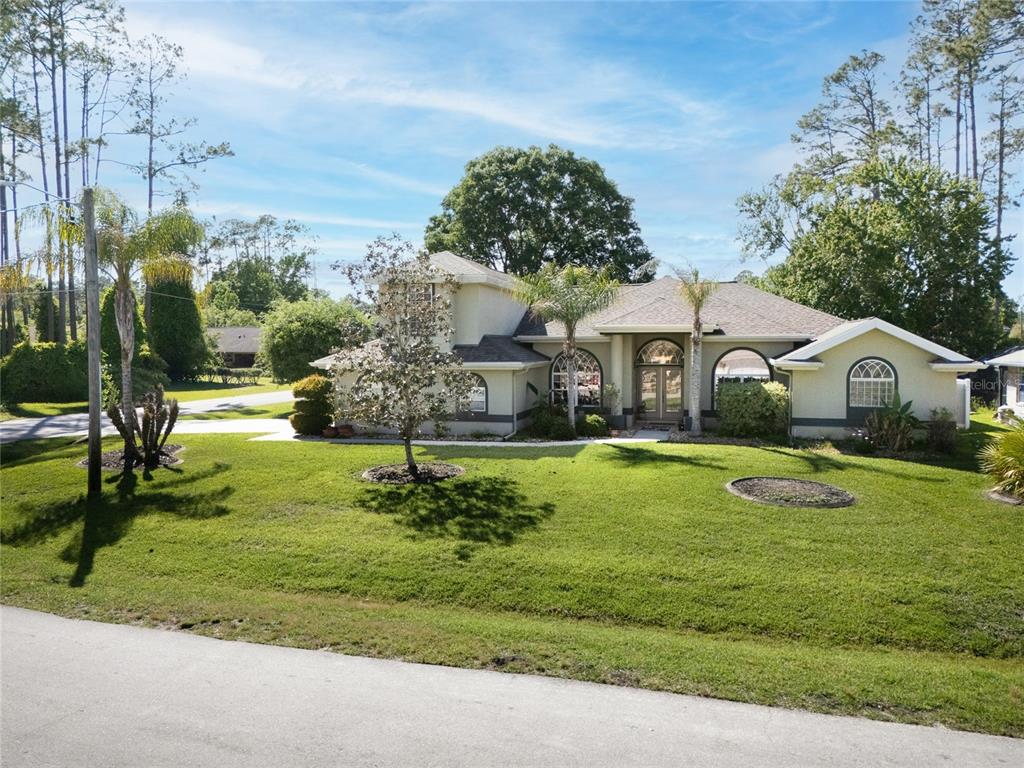 A two-story house with a beige stucco exterior and a large front lawn — 40 EDGEWATER DRIVE, PALM COAST, FL